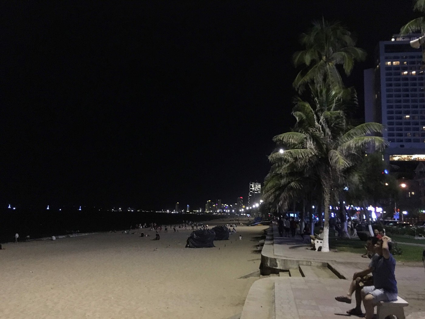 Nha Trang Beach at night with visitors walking along the shore