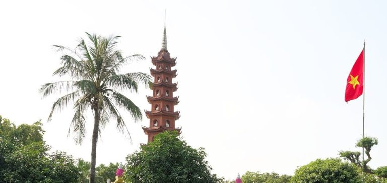 Phần trên bảo tháp chùa Trấn Quốc nổi bật giữa cây xanh trong ảnh năm 2024
