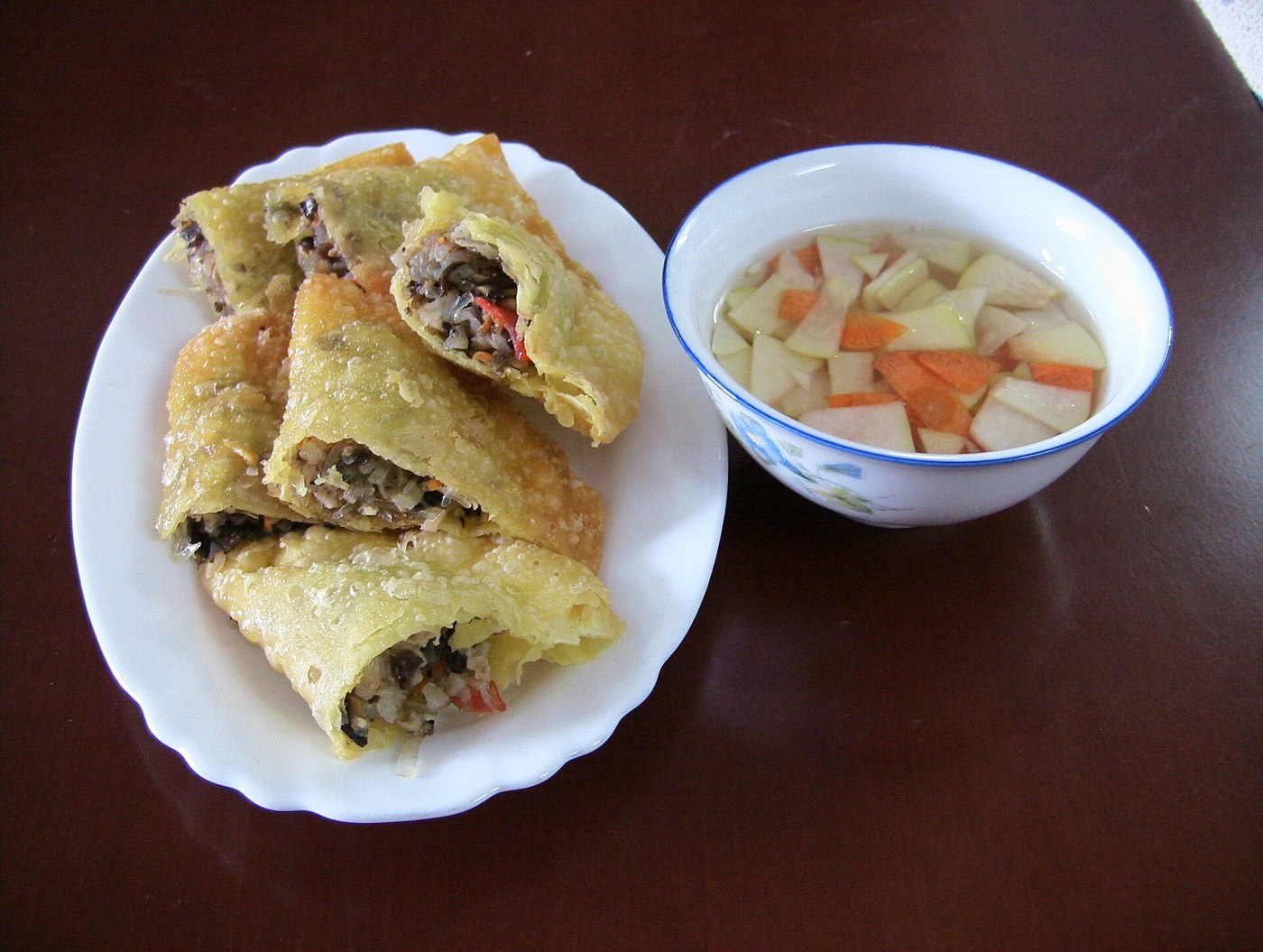 Bánh gối cắt mở để lộ nhân, bên cạnh bát nước chấm và đồ chua