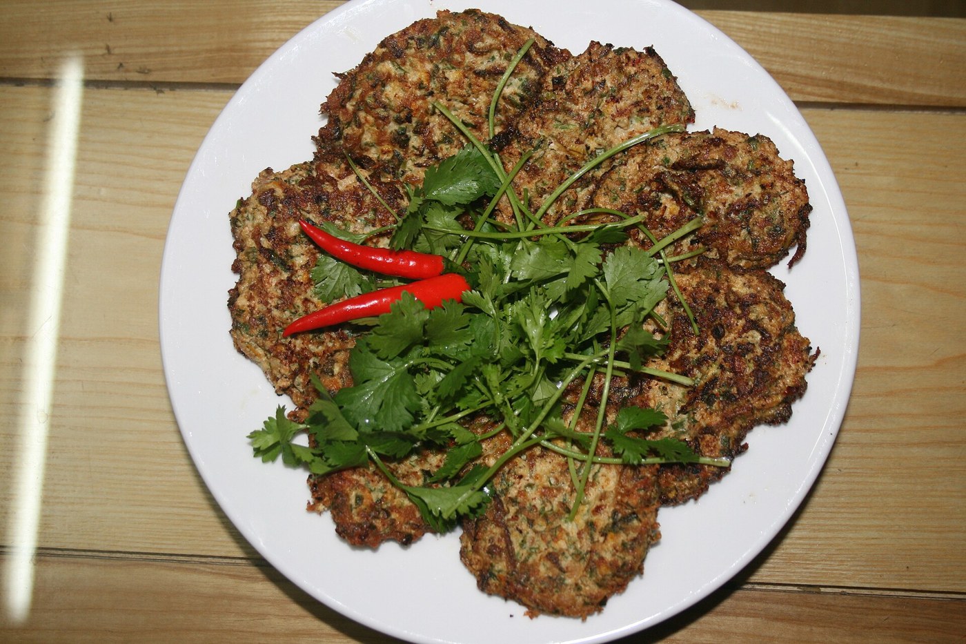 Đĩa chả rươi với bề mặt chiên nâu vàng và rau mùi ở giữa