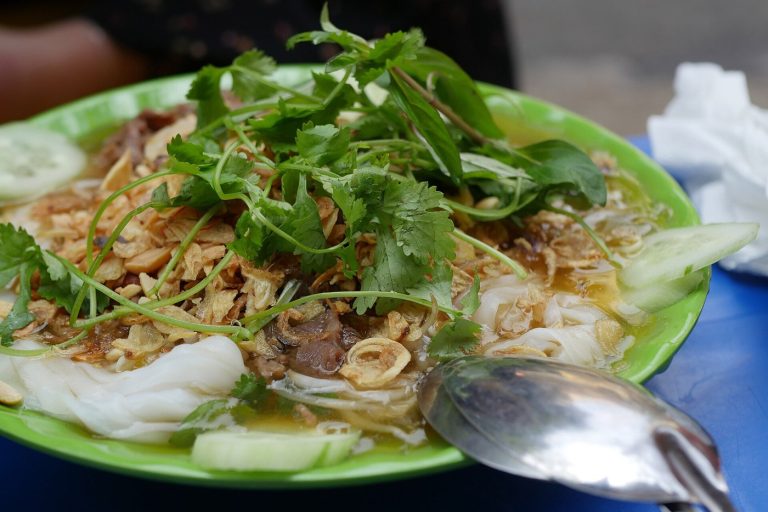 Đĩa bánh cuốn nóng với hành phi, rau thơm và nước chấm