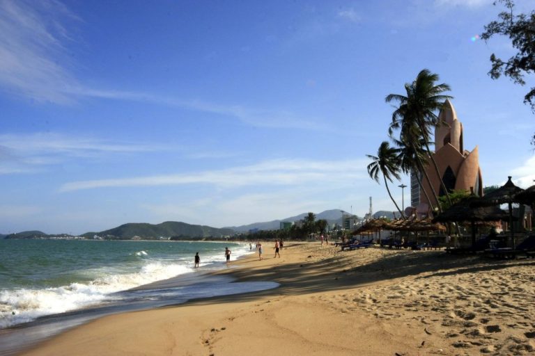 Bờ biển Nha Trang trong ngày nắng với Tháp Trầm Hương phía xa