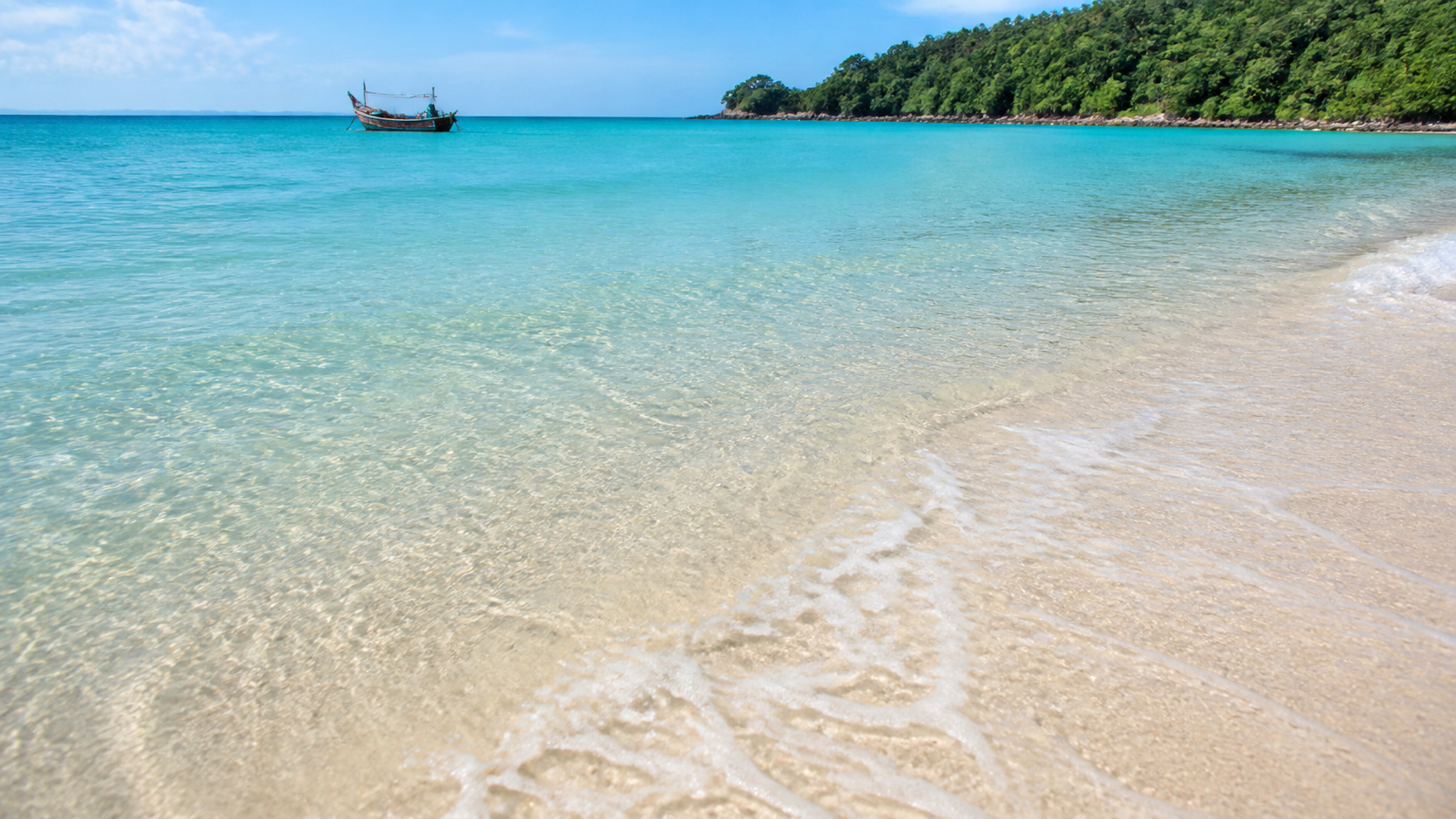 Sóng nhẹ trên cát sáng và thuyền nhỏ ngoài khơi Bãi Khem